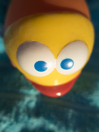 closeup of white and blue eyes of yellow fish plastic toyの写真素材