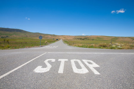 crossroad with stop symbol white painted on asphalt in rural road next to Madrid Spain Europeの写真素材