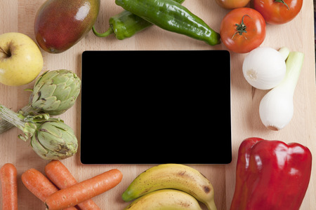 blank screen tablet still life fruits and vegetables around on brown wood plankの写真素材