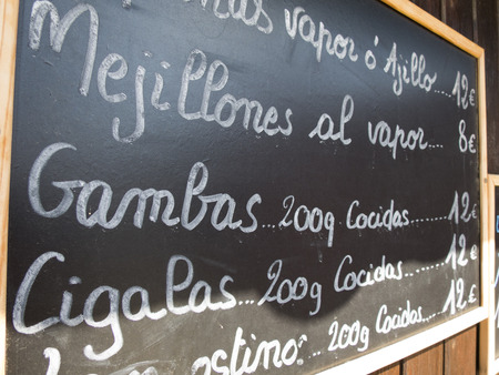 black placards spanish handwritten in brown wood wall with typical menu food dishes in Spain restaurantの写真素材