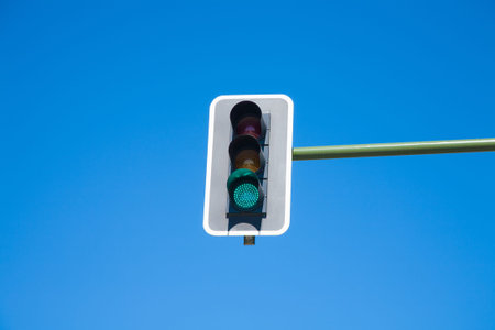traffic light semaphore green light on orange and red lights off  in green pole on blue sky horizontalの写真素材