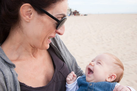 portrait of happy brunette woman mother grey shirt black sunglasses with two month age baby blue...