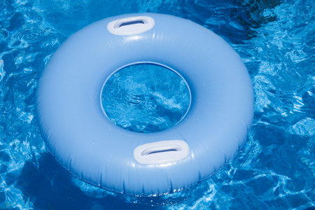 blue inflatable floater with two white handles in water of pool