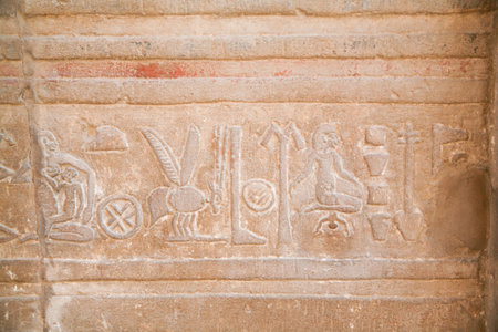 stone wall with Egyptian carving figures and hieroglyphs, with woman giving birth baby, other mother...