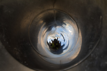 woman and little child playing sliding inside tube or pipe of great metal slide in playground with light at the end of tunnel or holeの写真素材