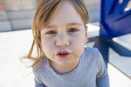 close up portrait of three years old child face, with grey shirt, looking at complaining and gesturing mouthの写真素材