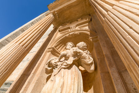 statue of monk with child in arms in baroque exterior door of Parish of Santa Ana, landmark and monument in Penaranda de Duero, Burgos, Castile and Leon, Spain, Europeの写真素材