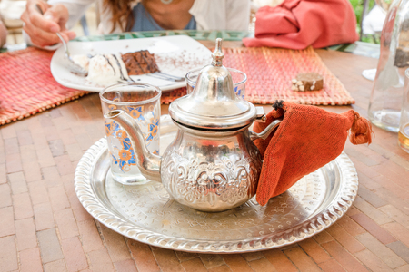 typical Moroccan metal teapot with glass vase and decorated tray, ready to serve, on tableの写真素材