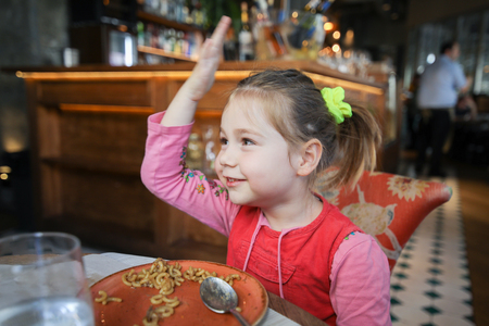 portrait of four years old blonde girl eating fideua, typical Spanish paella with noodles, smiling sitting in restaurantの写真素材