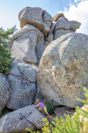 five years old blonde girl writing in a notebook in the Great Rock of Archpriest of Hita, in the mountains of Guadarrama Natural Park (Madrid, Spain, Europe)の写真素材