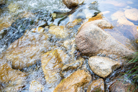beautiful detail of brilliant transparent water flowing on rocks in bed of river