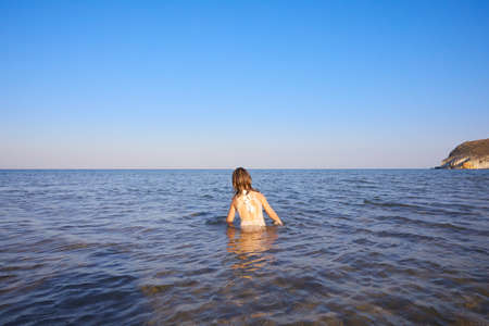 from behind little girl with swimsuit standing in the water of Mediterranean sea, in Cabo de Gata Natural Park (Almeria, Andalusia, Spain)の写真素材