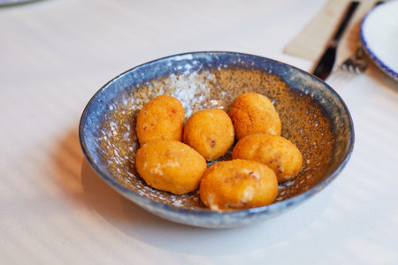 six croquettes in ceramic rustic nice bowl on a white tablecloth on the restaurant table