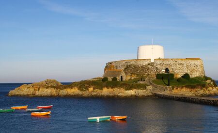 Fort Grey in a calm sea on a fine autumn morning. Situated on Guernsey's west coast at Rocquaine, at high tide Fort Grey becomes an islet that can be reached by causeway. The bay forms a protective harbour for local fishing boats that can be seen moored iのeditorial素材
