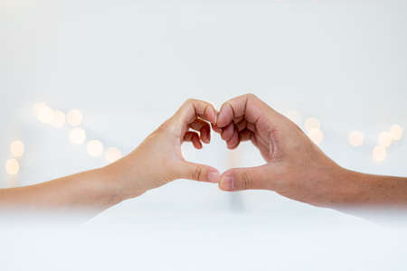 Man and woman hands making heart shape with fingers on white background.の写真素材