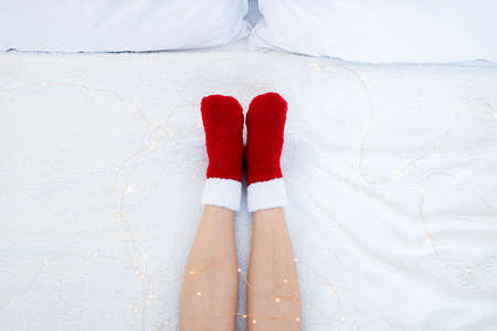 Woman's legs in red socks on the bed. Christmas and New Year concept.の写真素材