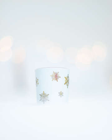 White cup with snowflake design on white background with bokehの写真素材