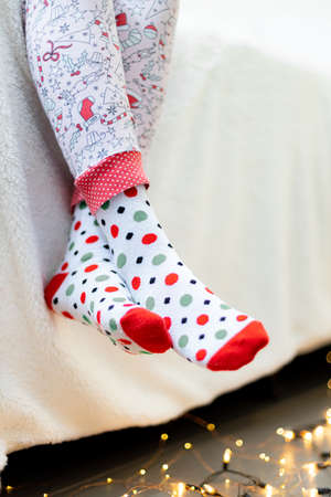 Womens feet in colorful socks on the bed. Christmas concept.の写真素材