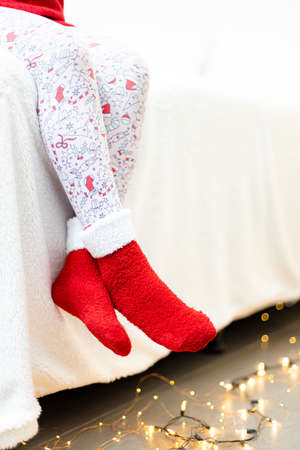 Close-up of female legs in red christmas socks on the bedの写真素材