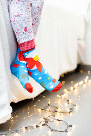Close up of childs feet in colorful socks with Christmas lights.の写真素材
