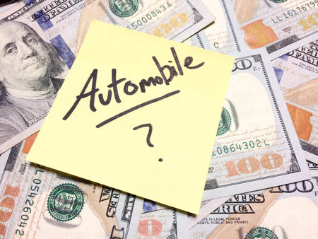 American cash money and yellow sticky note with text Automobile with question mark in black color...