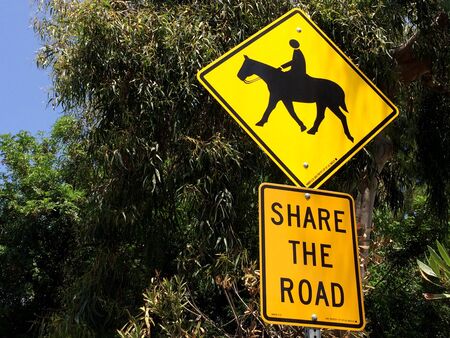 Horse crossing sign yellow with green trees near roadsideの写真素材