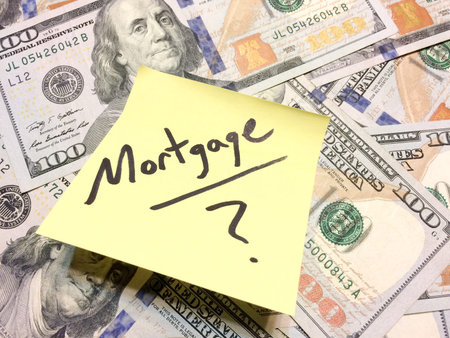 American cash money and yellow post it note with text Mortgage with question mark in black color...