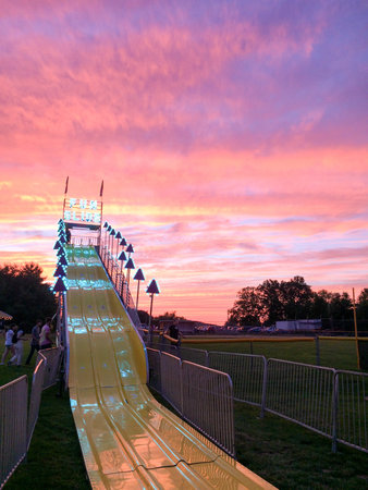 giant fun slide at fairgrounds at sunset with colorful sky