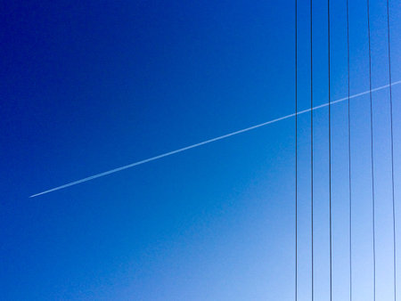 Electric power lines with jet stream and blue sky