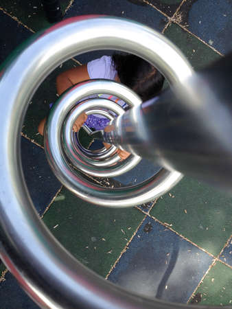 cute kid girl smiling at playground climbing up ladder spiralのeditorial素材