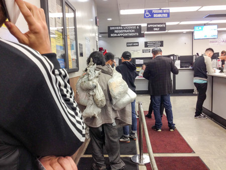 Department of motor vehicles DMV California America homeless people waiting in crowded line indoor...