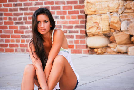 Beautiful girl brunette hazel brown eyes sitting street outdoors summer seasonの写真素材