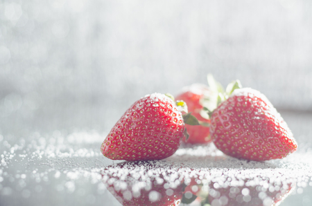 Strawberries with reflection and sugar in bright light.の写真素材