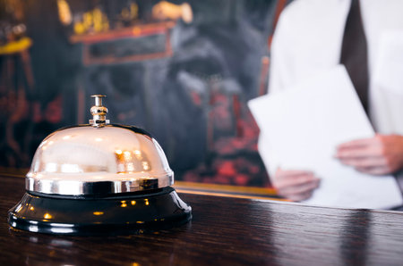 Hotel reception service bell with concierge holding a file in backgroundの写真素材
