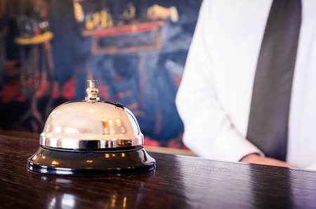 Hotel reception service bell with concierge welcoming in the backgroundの写真素材