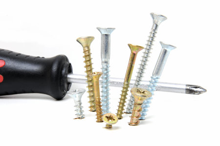 Black screwdriver and drywall screws over white background 