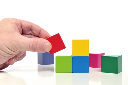 Final step to success - Human hand and multicolored toy blocks on white backgroundの写真素材