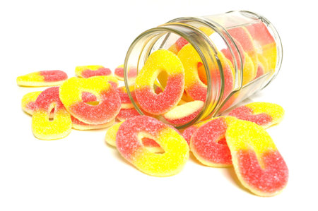 Peach flavored candy rings and glass jar on white background 