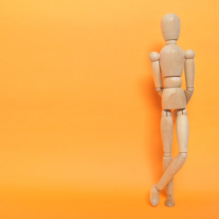 Cool wooden man in front a orange colored wall の写真素材