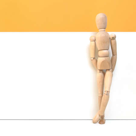 Relaxed wooden man in front of a white wall の写真素材