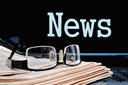 Newspaper with glasses below the laptop monitor lettering news の写真素材