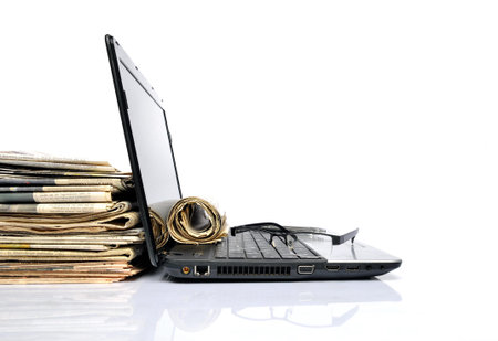Folded newspapers and a black laptopの写真素材