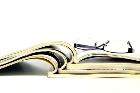 Stack of open magazines with black glassesの写真素材