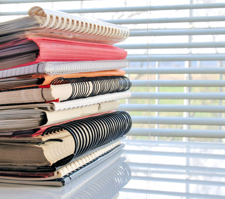 Stack of office folders and ring binders in front of a window