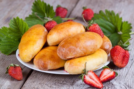 Fresh baked pasties with strawberries on plate close-upの写真素材