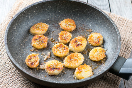 Caramelized bananas in a frying pan on wooden tableの写真素材