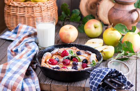 Dutch baby pancake with apple and cinnamon on an old wooden table backgroundの写真素材
