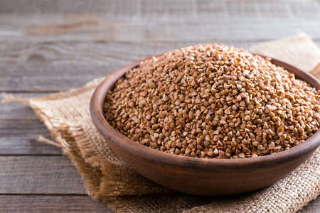 Buckwheat groats in  bowl on wooden backgroundの写真素材