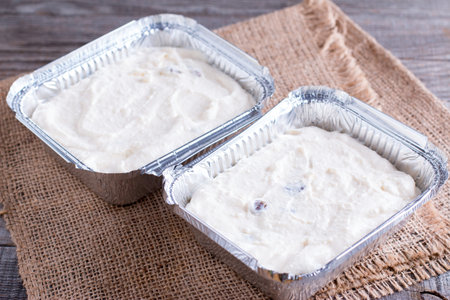 Cottage cheese casserole in foil tray on wooden tableの写真素材