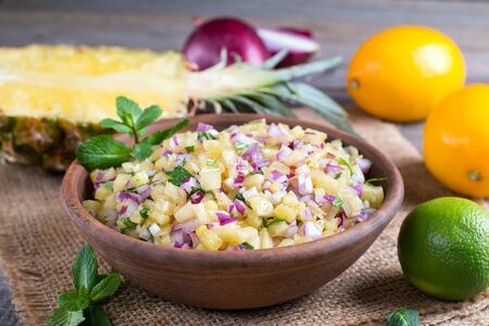 Pineapple salsa with fruit and mint in a bowl on the tableの写真素材